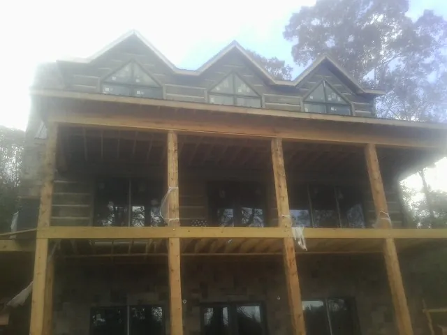 Dormers and porch framing on a large log home under construction — Roof Coating work by our crew in Halifax